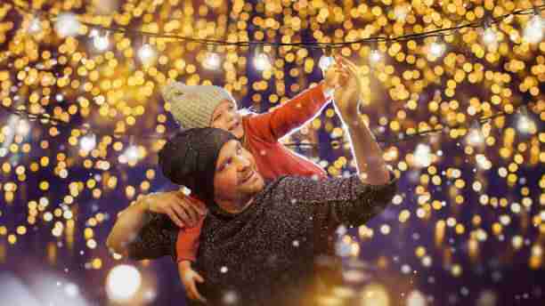 A father and child enjoying a beautifully lit holiday display, highlighting the joy brought by expert holiday lights installation at 12900 Valley Branch Lane Suite 408 Farmers Branch, TX 75234.